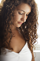 Woman with long curly hair looking down - Alex Mares-Manton