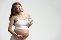Pregnant woman standing, glass of milk in hand - Alex Mares-Manton