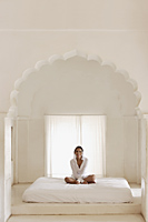man sitting on bed in white room - Alex Mares-Manton