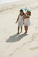 two girls walking on beach under blue umbrella - Alex Mares-Manton