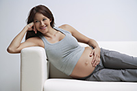 Pregnant woman reclining on couch, smiling - Alex Mares-Manton
