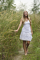 Blond woman on grassy path, hand on tall grass - Alex Mares-Manton