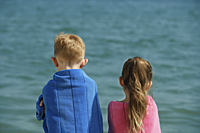 boy and girl watching ocean, wrapped in towels - Alex Mares-Manton