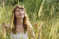 Red haired woman standing in tall grass, smiling - Alex Mares-Manton