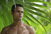 man under giant leaf in rain shower - Alex Mares-Manton