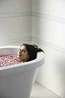 woman in bath tub with floating petals - Alex Mares-Manton