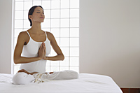 woman in yoga position on white bed - Alex Mares-Manton