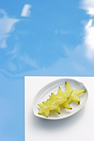 Sliced star fruit on plate, pool - Alex Mares-Manton