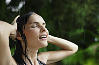 woman in tropical rain shower, hands on head - Alex Mares-Manton