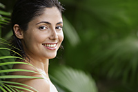 Woman in tropical garden, smiling - Alex Mares-Manton