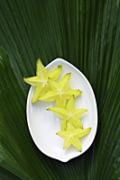 Star fruit (sliced) on white plate - Alex Mares-Manton