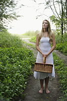 Blond woman standing on pathway holding basket - Alex Mares-Manton