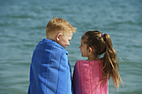 boy and girl at beach, wrapped in towels - Alex Mares-Manton