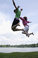 Teen girls jumping by lake - Nugene Chiang