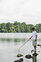Teen boy holding stick in lake - Nugene Chiang