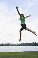 Teen girl jumping by lake - Nugene Chiang