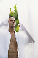 Man standing between open white curtains - Alex Mares-Manton