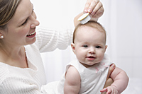 Mother brushing baby's hair - Alex Mares-Manton