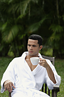 Man drinking coffee outside, wearing robe - Alex Mares-Manton