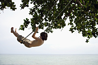 Boy swinging by ocean - Alex Mares-Manton