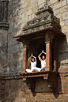 Couple in yoga posture, sitting in ancient monument - Alex Mares-Manton