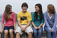 Group of teens sitting on wall next to lake - Nugene Chiang