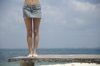 legs of woman standing near ocean - Nugene Chiang