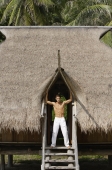 Young man standing in doorway of island house - Alex Mares-Manton