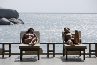 couple on lounge chairs overlooking ocean - Alex Mares-Manton