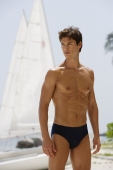 man standing in bathing suit in front sail boat - Alex Mares-Manton
