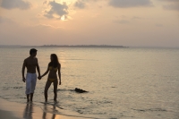 Couple walking on beach in sunset - Alex Mares-Manton