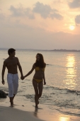 Couple walking on beach in sunset - Alex Mares-Manton