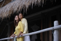 young couple standing on balcony of tropical home - Alex Mares-Manton