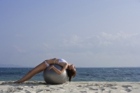 woman in bikini lying on giant ball on beach - Alex Mares-Manton