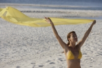 woman in yellow bikini holding yellow fabric on beach - Alex Mares-Manton