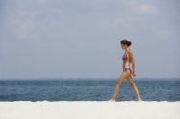 young woman walking in bathing suit on beach - Alex Mares-Manton