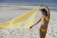 woman in yellow bikini holding yellow fabric on beach - Alex Mares-Manton