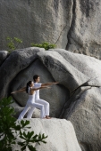 couple doing yoga on rock - Nugene Chiang