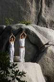 couple doing yoga on rock - Nugene Chiang