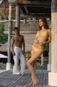Woman in yellow bikini, man standing in background - Alex Mares-Manton