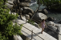 young woman standing on bridge looking at ocean - Alex Mares-Manton