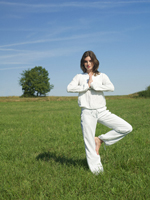 Young woman standing in yoga pose in meadow - Alex Hajdu