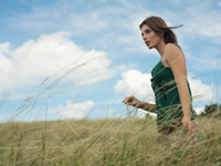 Young woman walking in grassy field - Alex Hajdu