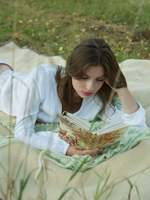 Young woman reading on blanket outdoors - Alex Hajdu
