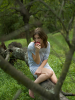 Young woman eating apple in woods - Alex Hajdu