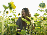 Young woman standing amid sunflowers - Alex Hajdu