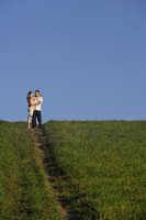 Young couple embracing on top of hillside - Alex Mares-Manton