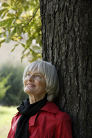 Senior woman leaning against tree - Alex Mares-Manton