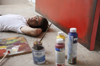 artist lying on ground with paints - Dennison Bertrand
