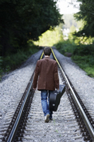 Young man walking down train tracks with guitar - Alex Mares-Manton